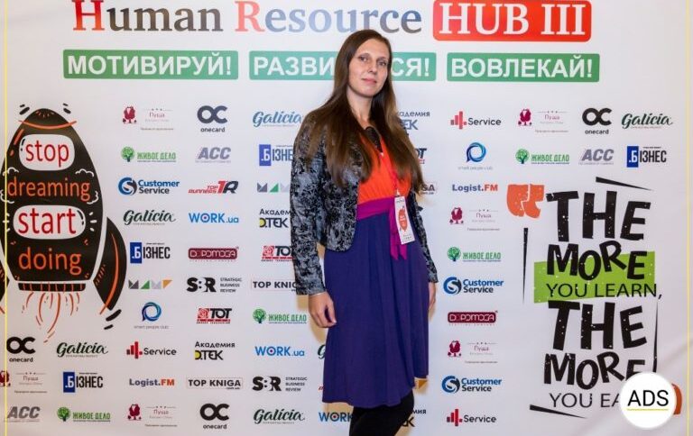 Учасниця конференції Human Resource HUB III на фоні бренд-воллу з логотипами партнерів: стратегія